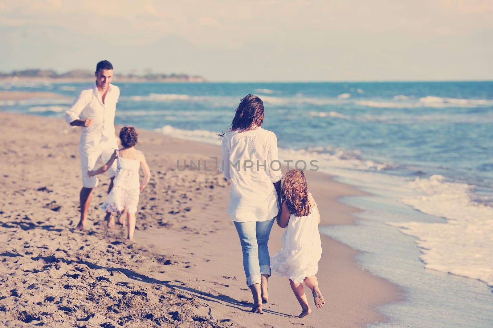 happy young family in white clothing have fun at vacations on beautiful beach 