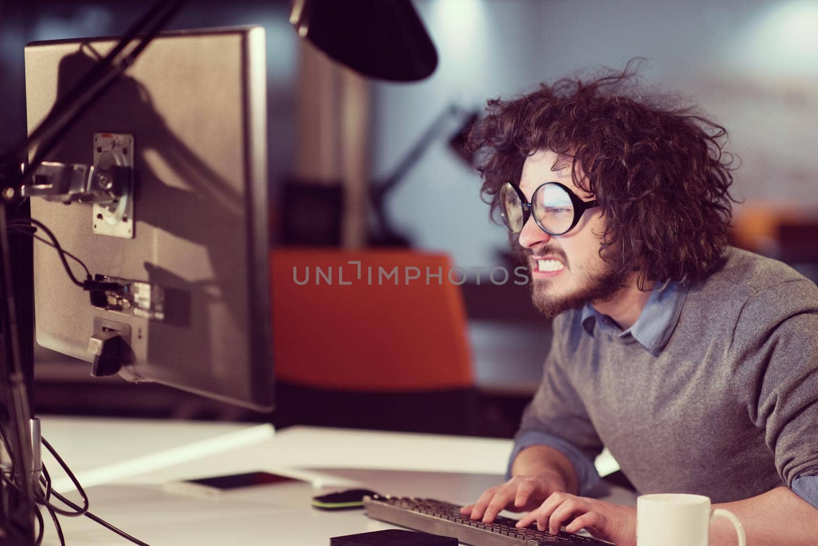 man working on computer in dark startup office by dotshock