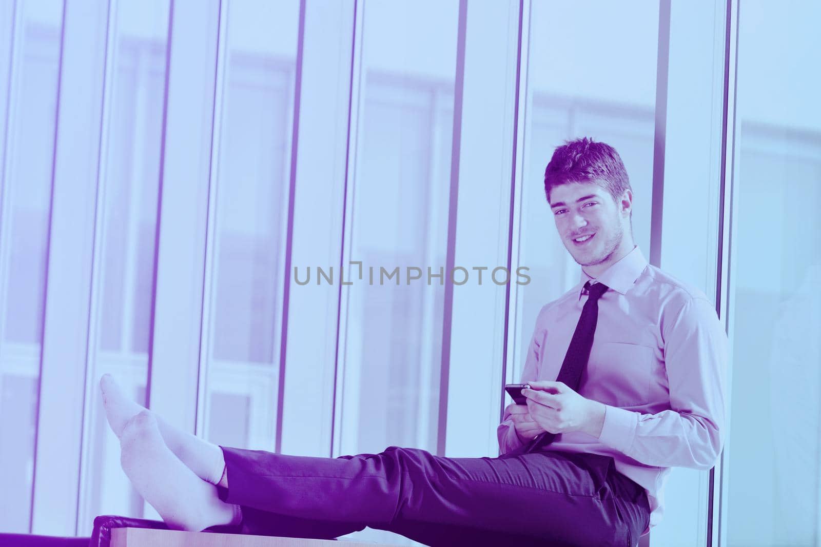 young business man talk by cellphone over bright window in big hall