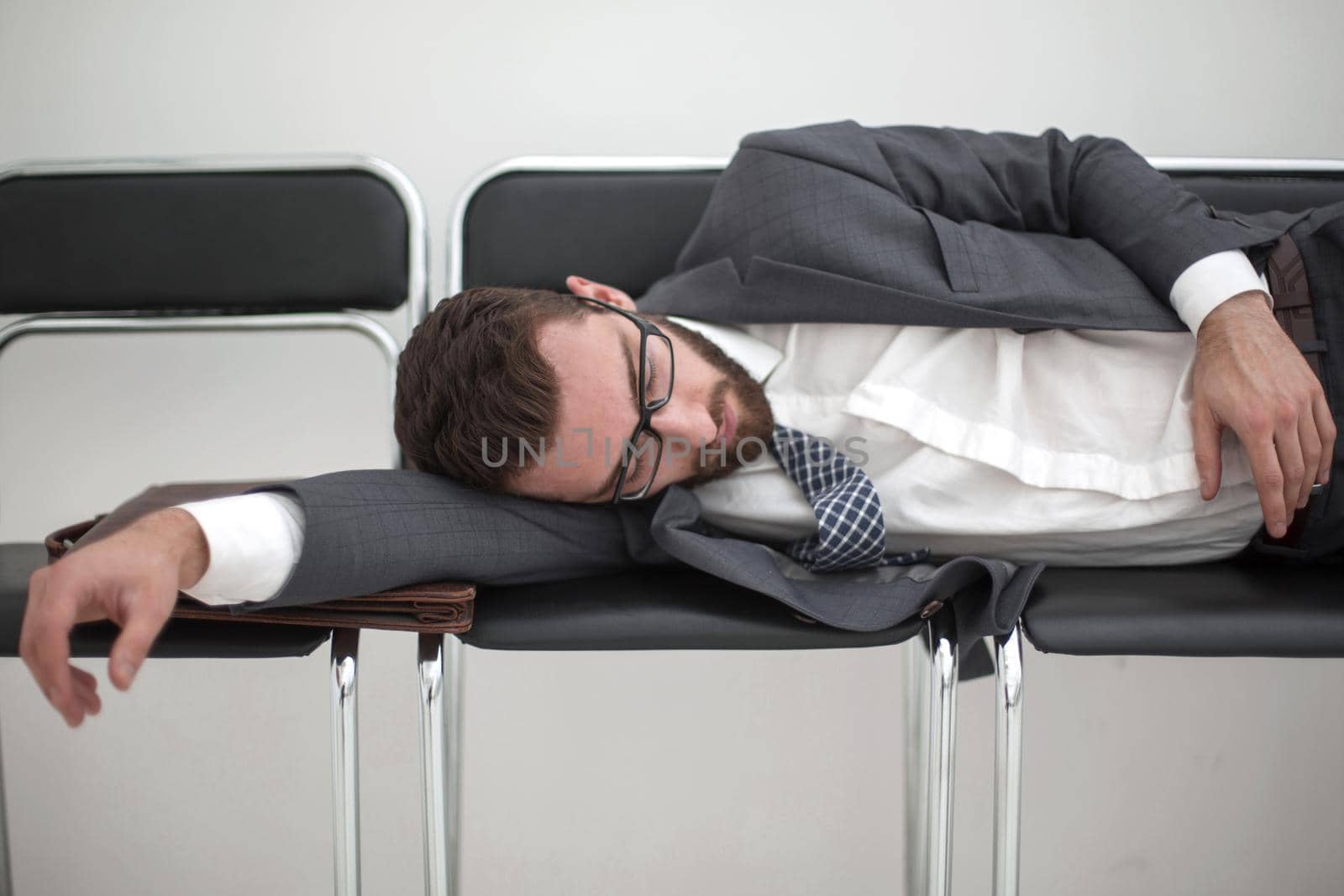 tired businessman sleeping on chairs in the office hallway.the concept of waiting