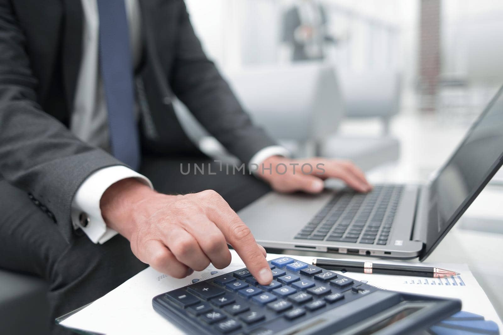 close up.a businessman uses a calculator and a laptop. by asdf
