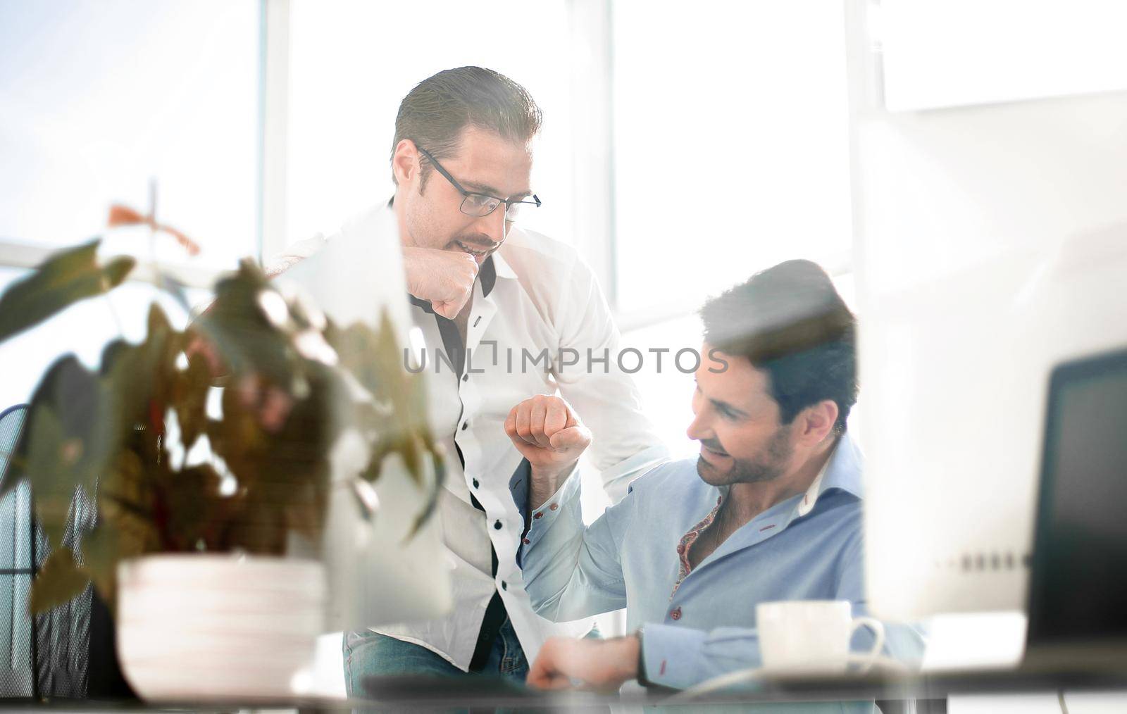 business background.Two smiling male colleagues giving fist bumps. concept of achieving a business goal