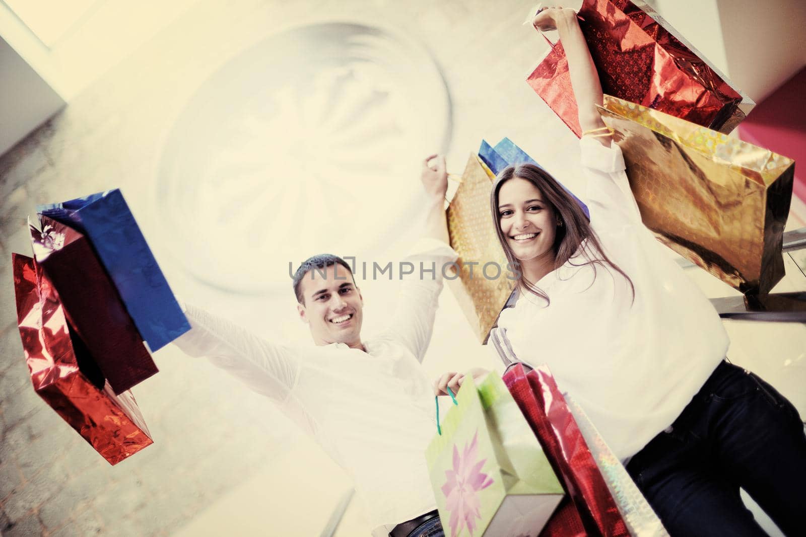 happy young couple with bags in shopping centre mall