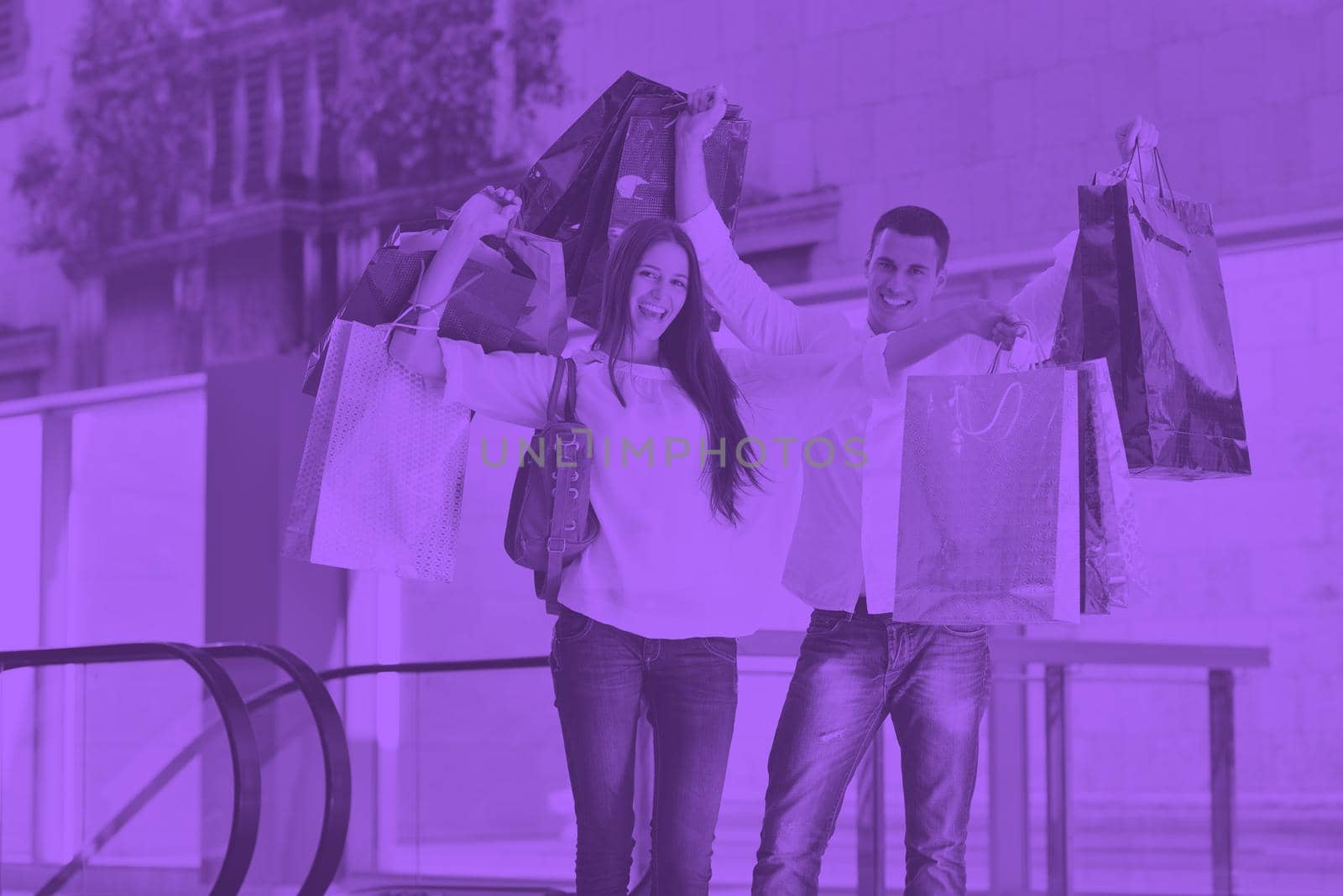 happy young couple with bags in shopping centre mall