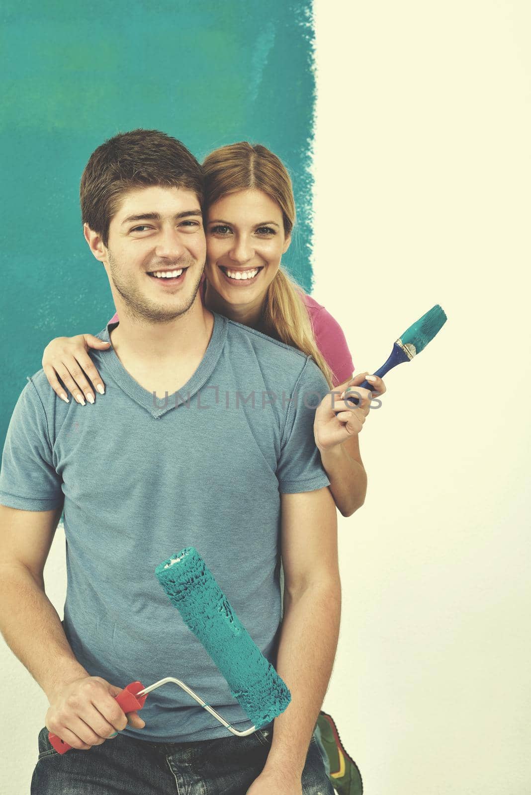 happy young couple paint in green and blue color white wall of their new home