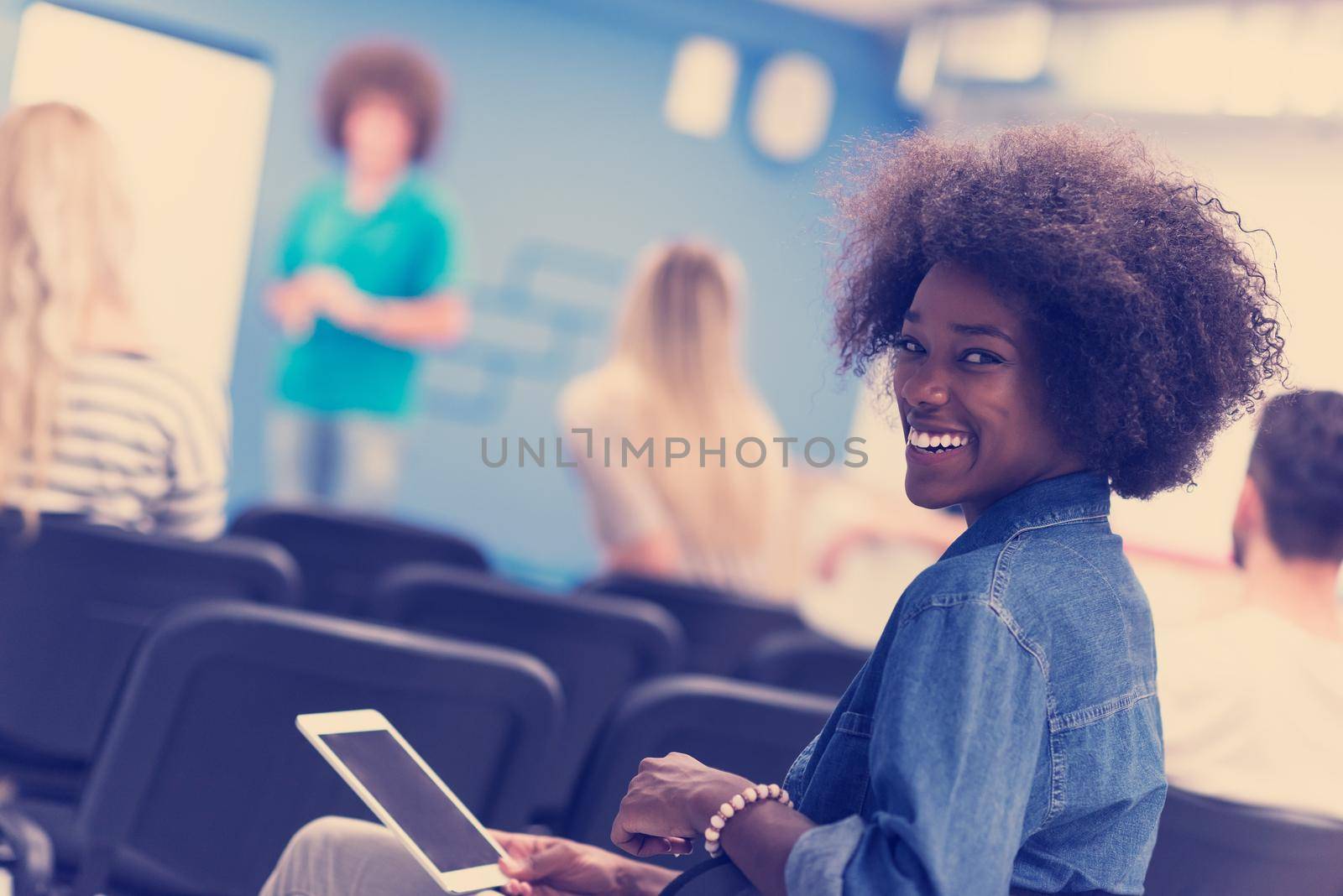 portrait of young African American business woman at modern startup office interior, team in meeting in background