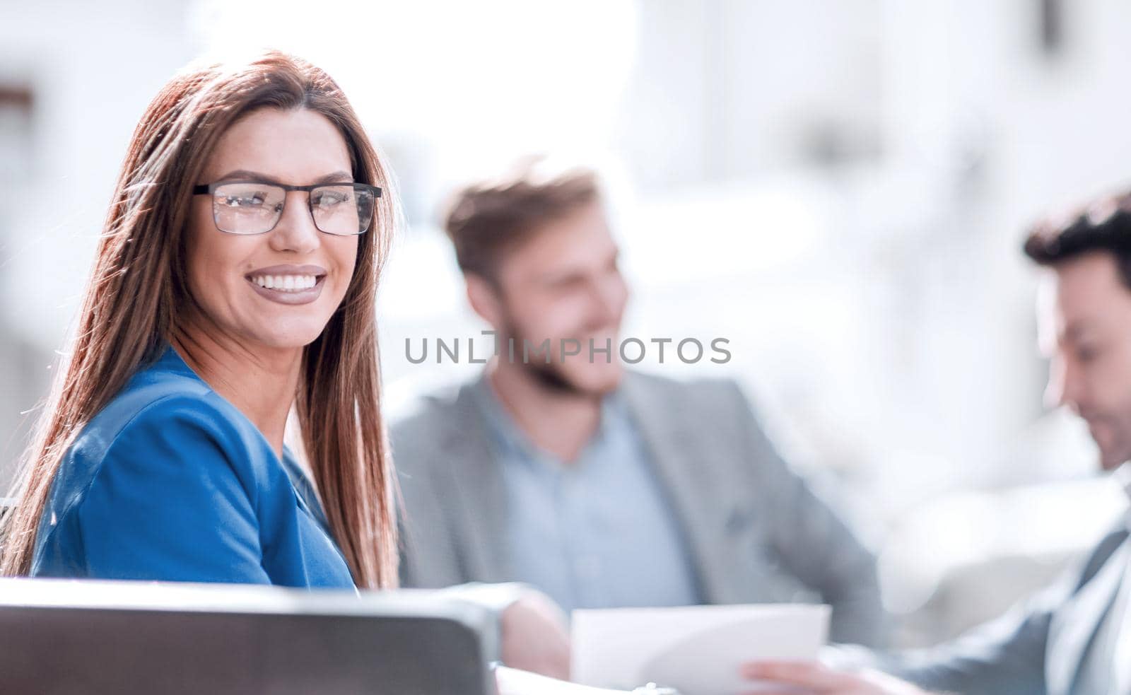 business woman sitting at a table on the background of colleagues by asdf