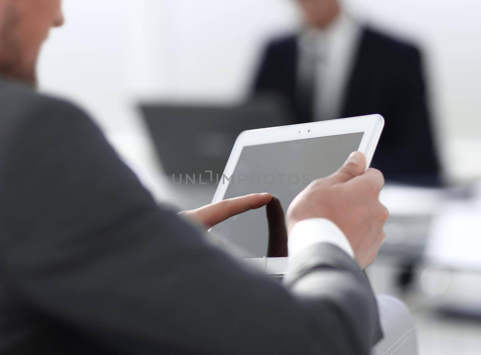 businessman in suit in modern office using tablet by asdf