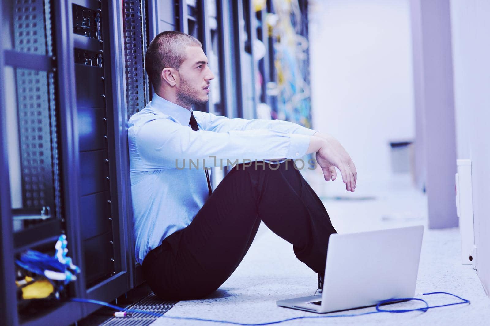 young engeneer business man with thin modern aluminium laptop in network server room