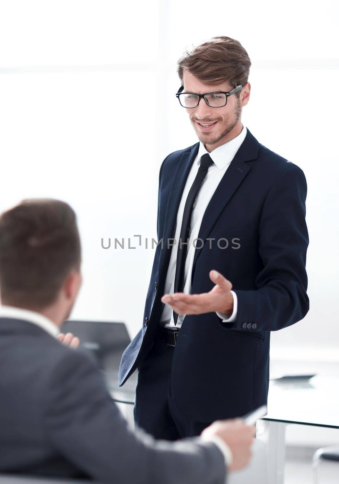two businessmen at the office greeting each other by the hand and smiling