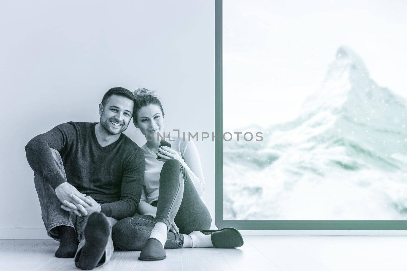 happy young couple sitting near window at home on cold winter day