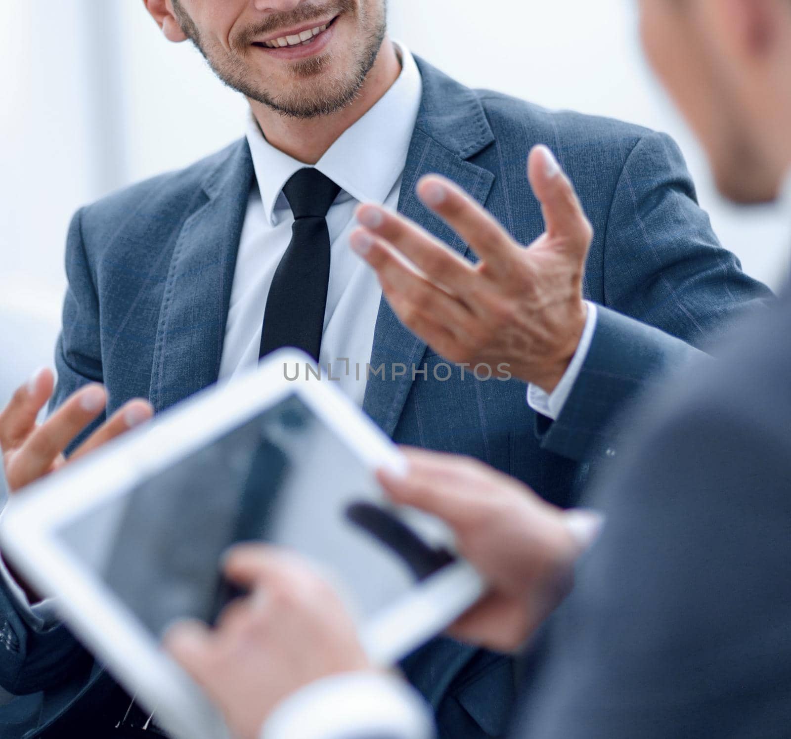 Image of two young businessmen using touchpad at meeting by asdf