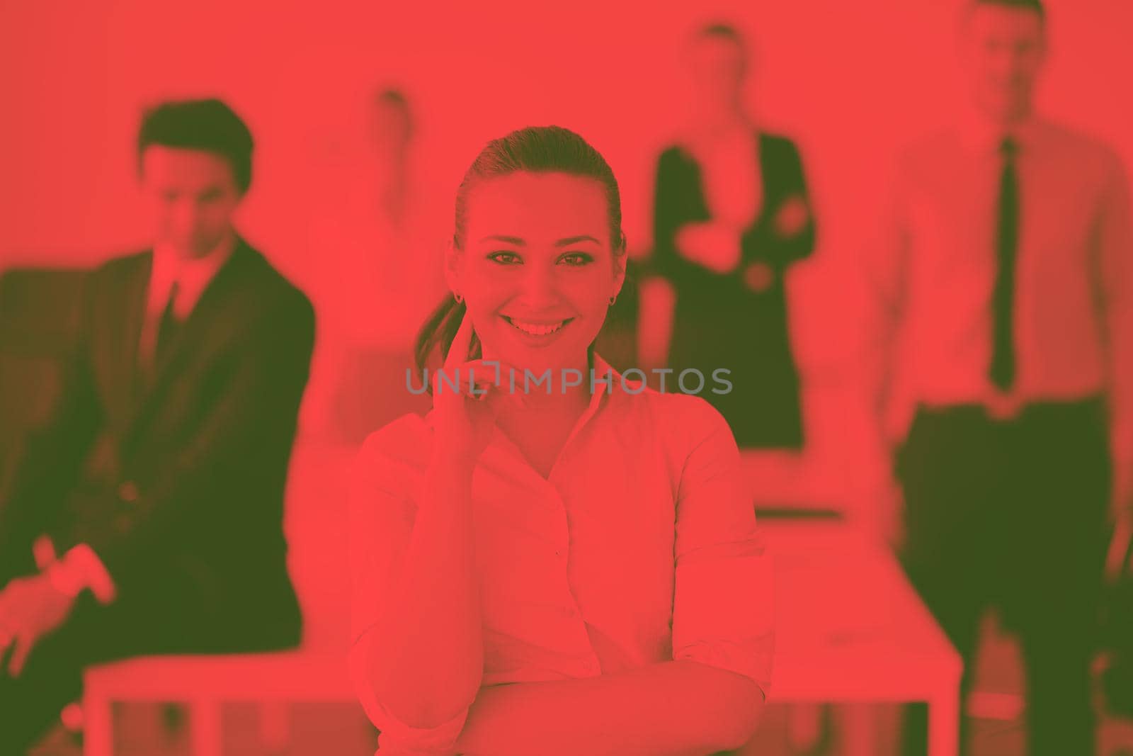 Successful business woman standing with her staff in background at modern bright office