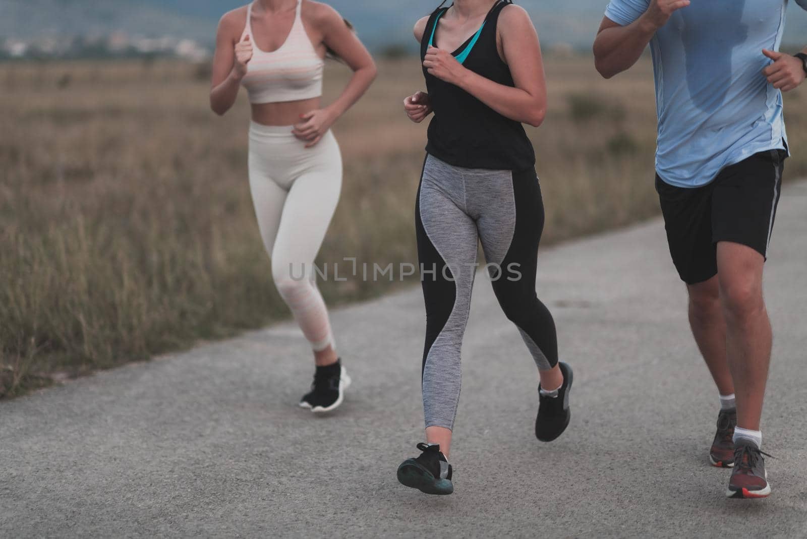 Three multiethnic women runners group wear face masks running keep social distance outdoor. Fit healthy diverse team wear sportswear jogging in park on nature sport track distancing for safety. by dotshock