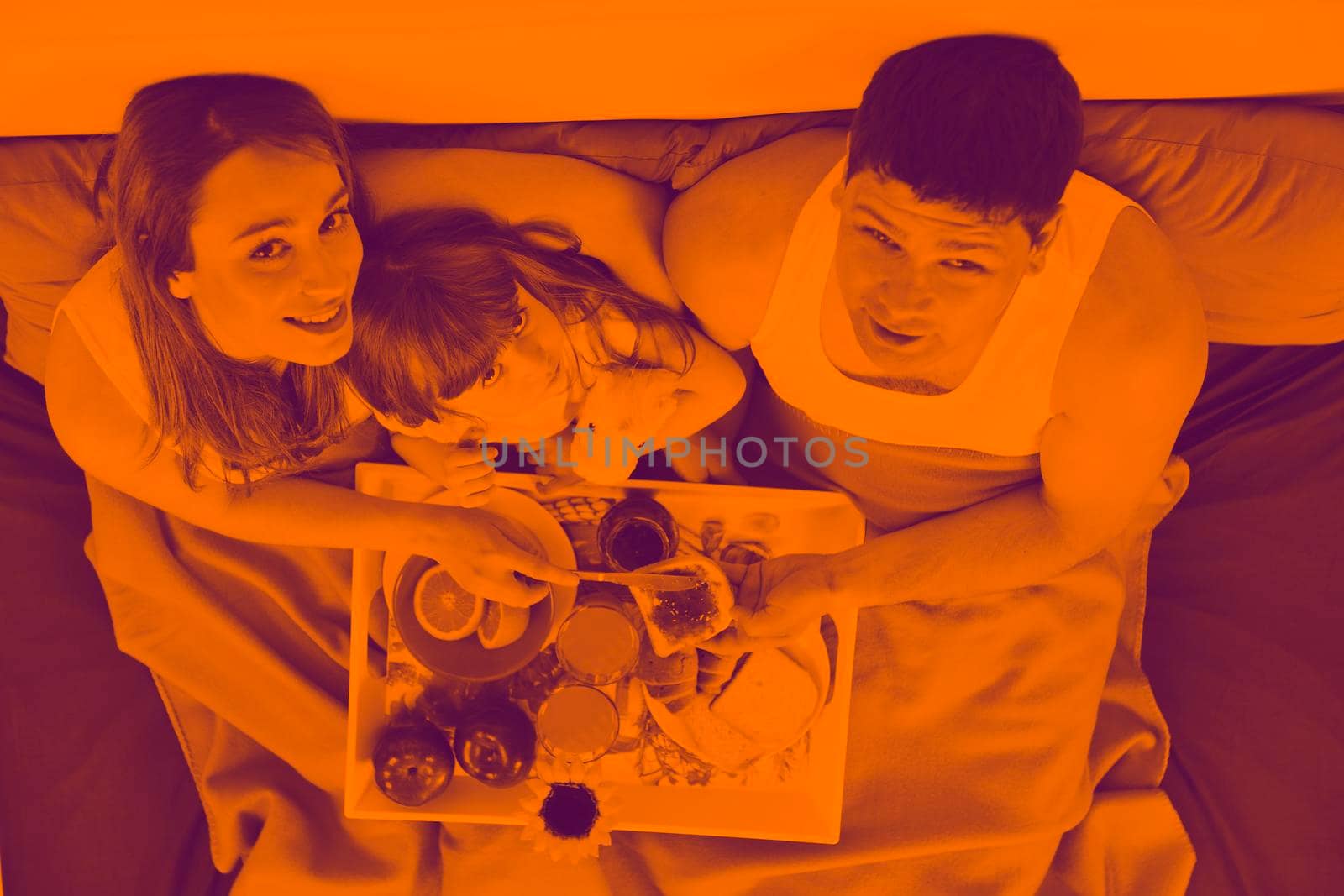 happy young family eat breakfast in bed at morning duo tone