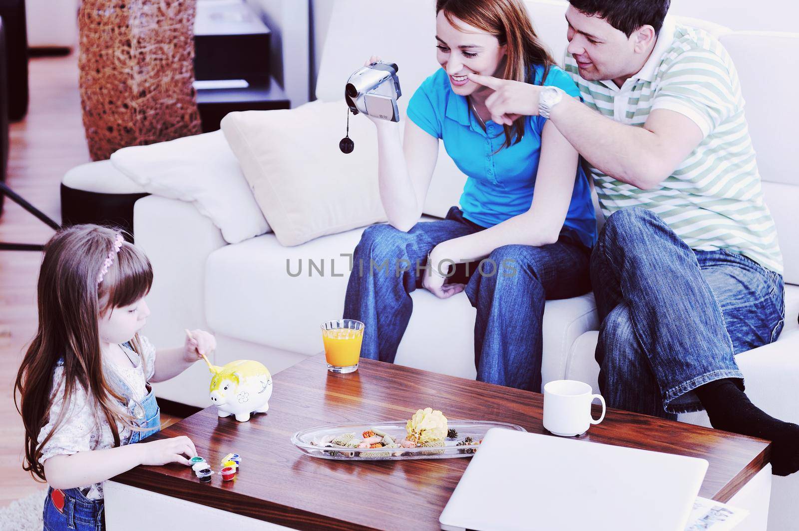 young happy family recording by video camera their child at home