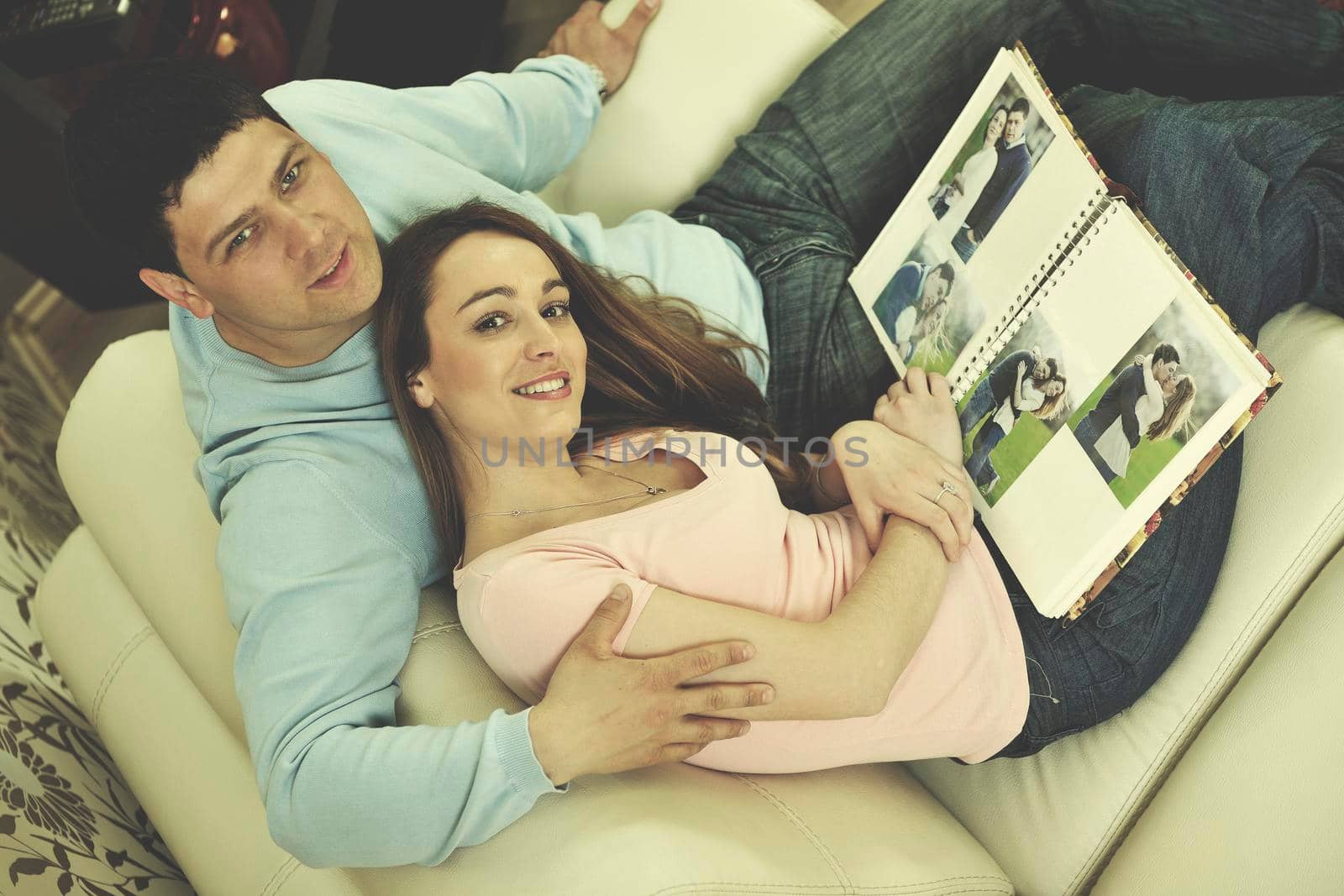 happy young couple looking old pictures in photo album at home