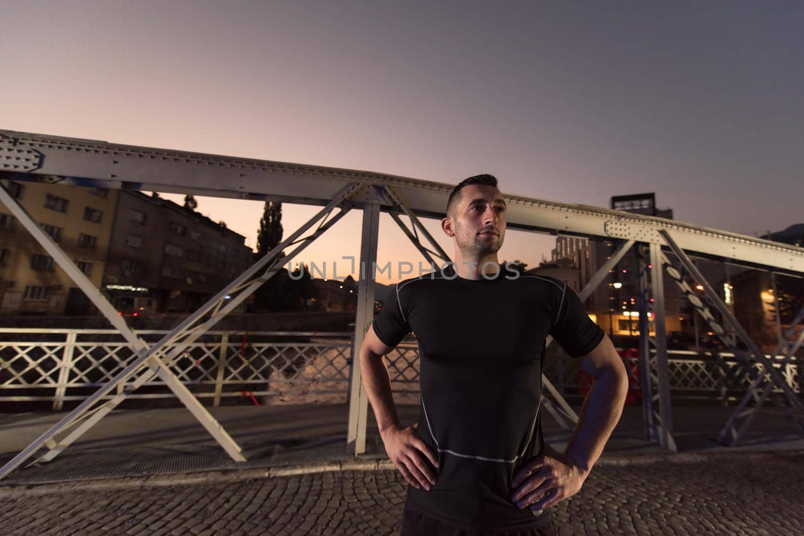 urban sports, young healthy man jogging across the bridge in the city at early morning in night