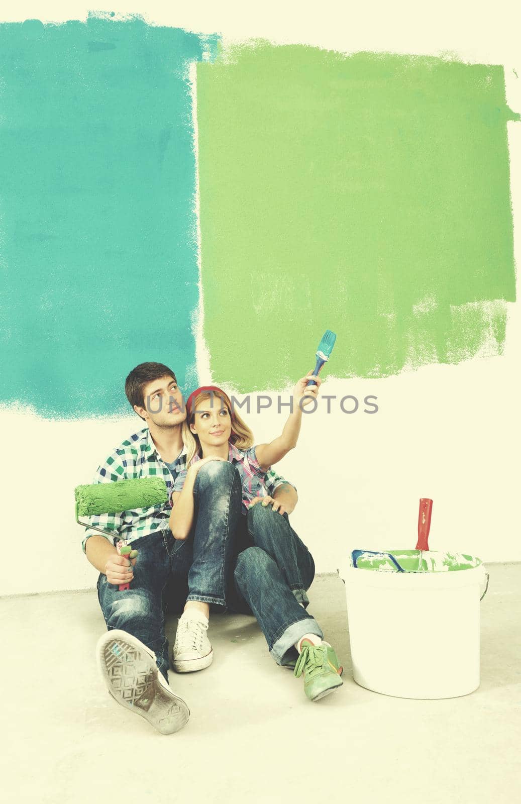 happy young couple paint in green and blue color white wall of their new home