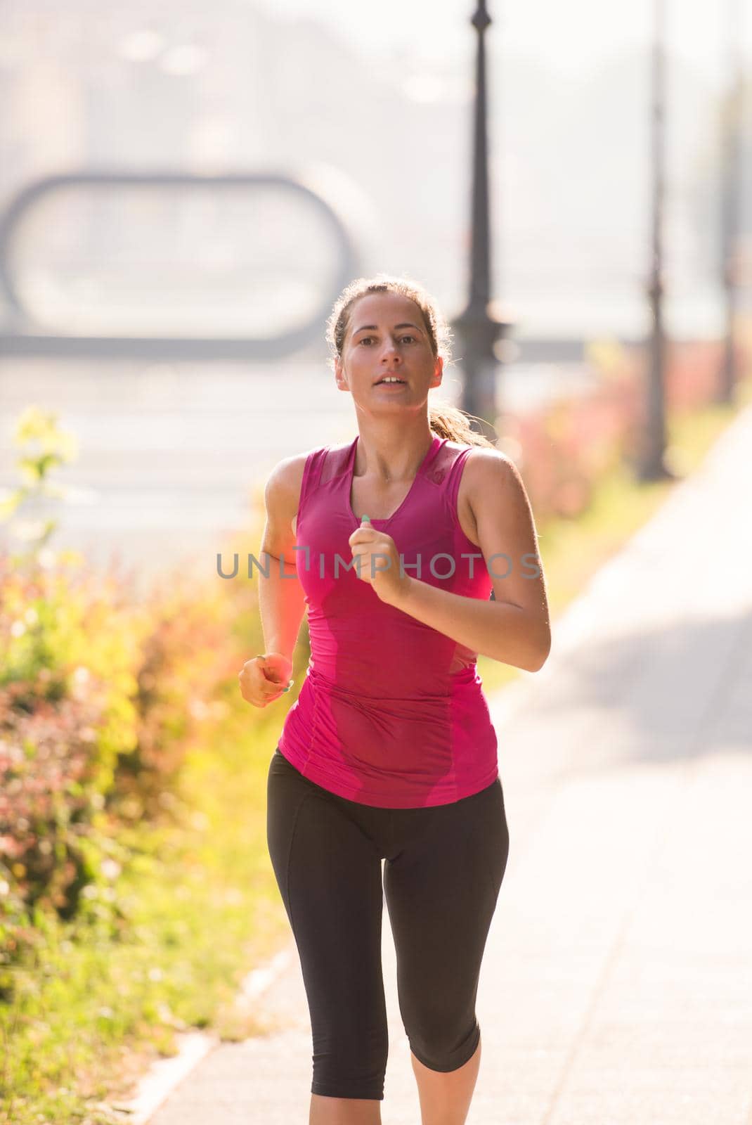 young sporty woman jogging at sunny morning in the city