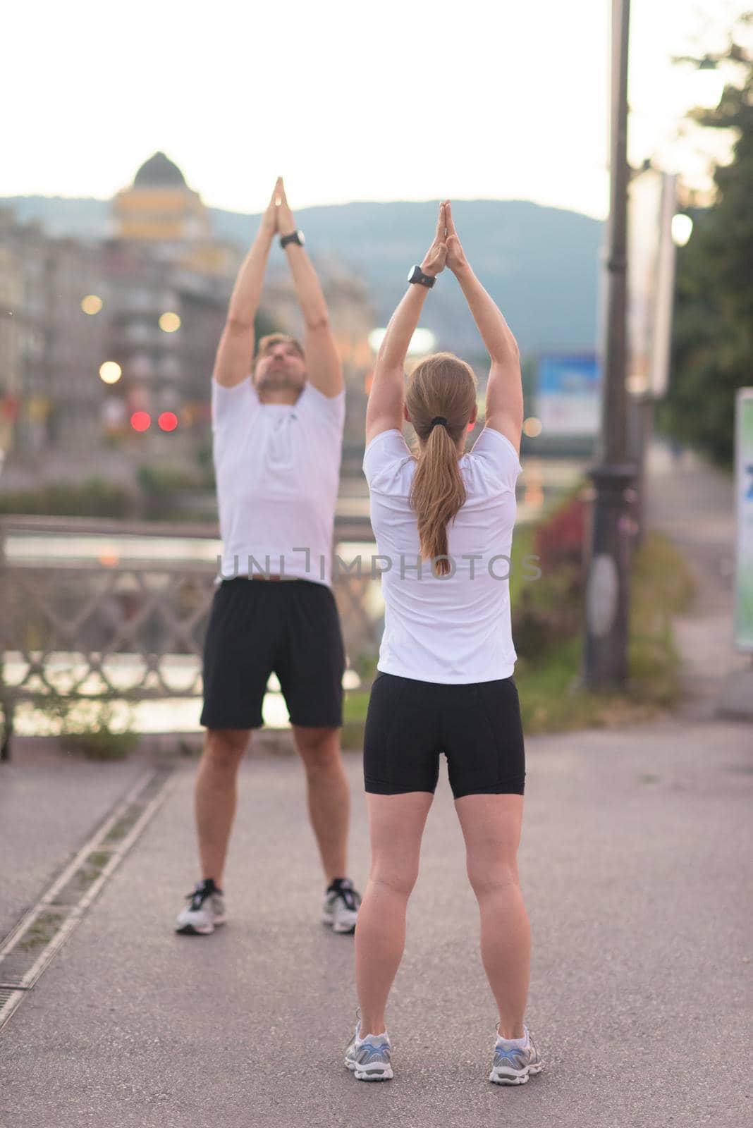 jogging couple warming up and stretching before morning running in the city