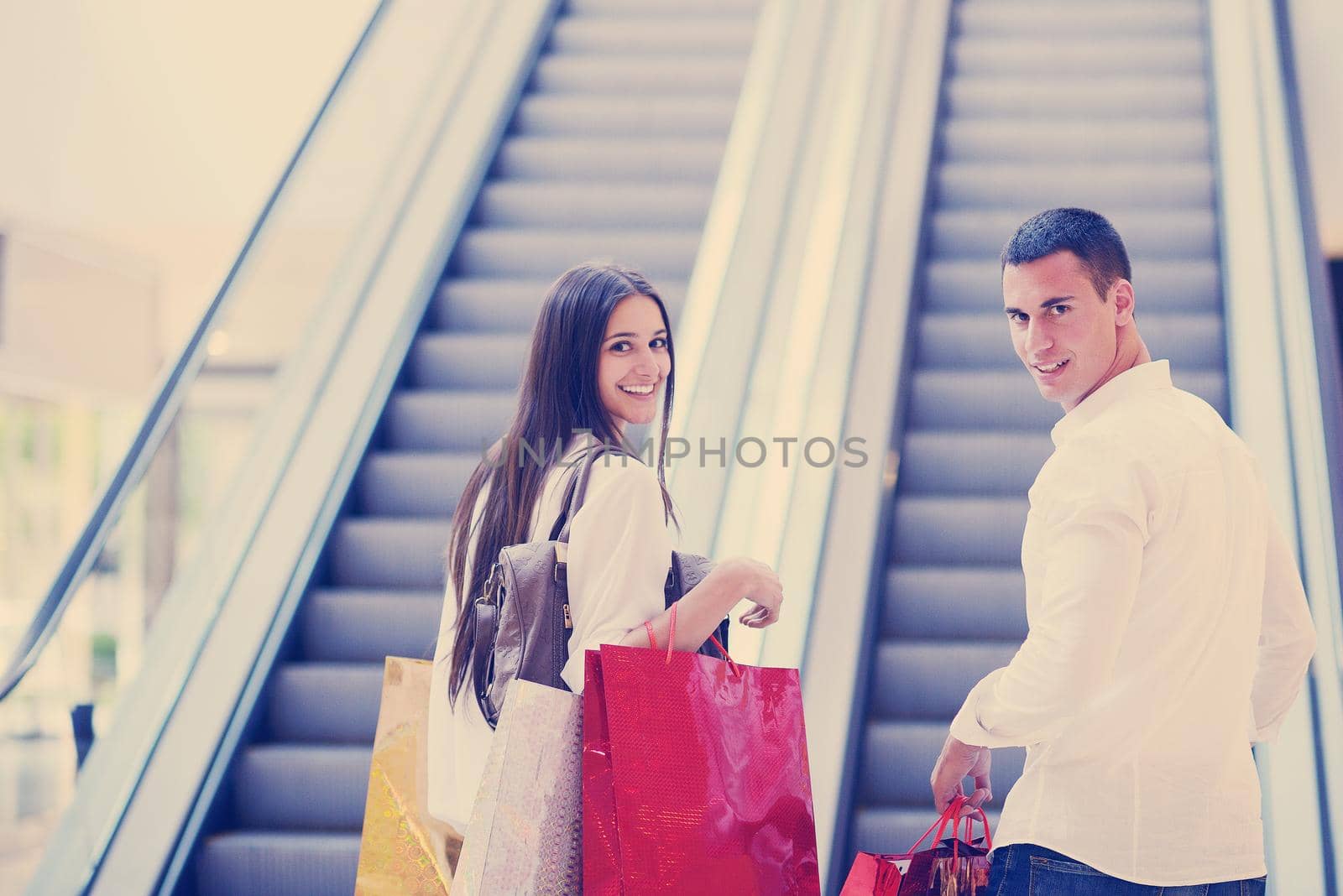 happy young couple with bags in shopping centre mall