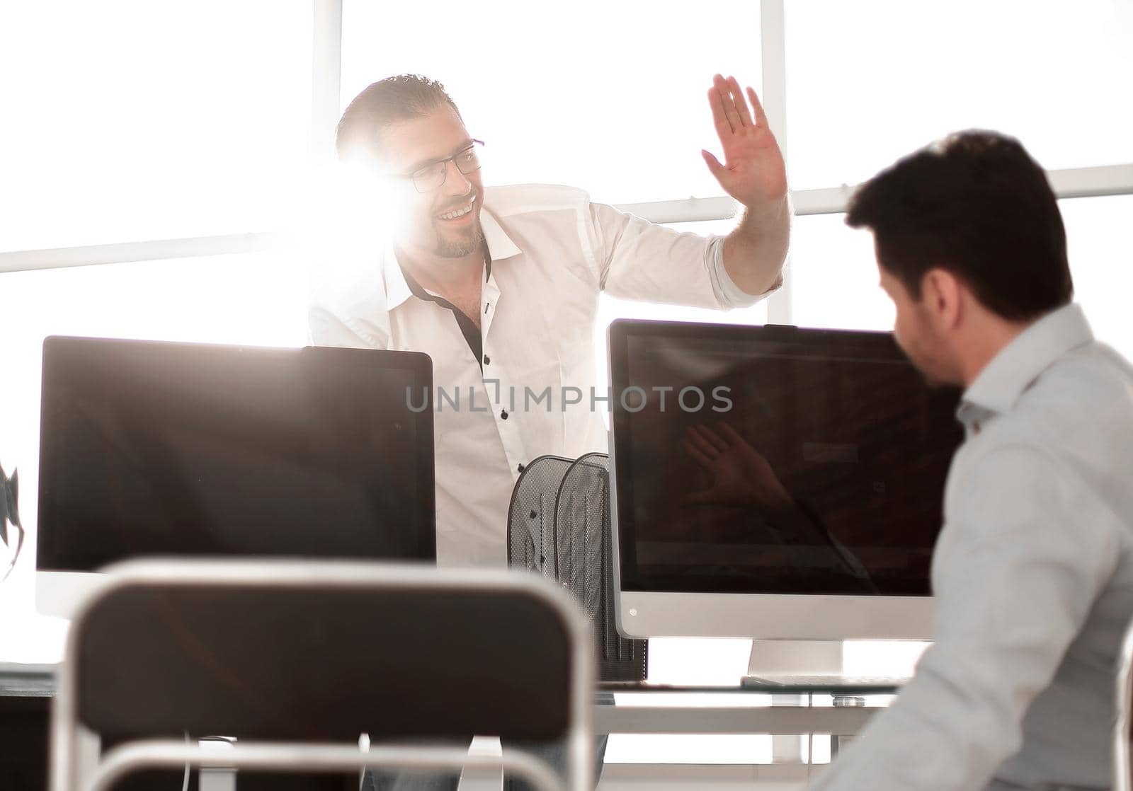 employees give each other a high five over the computer Desk by asdf