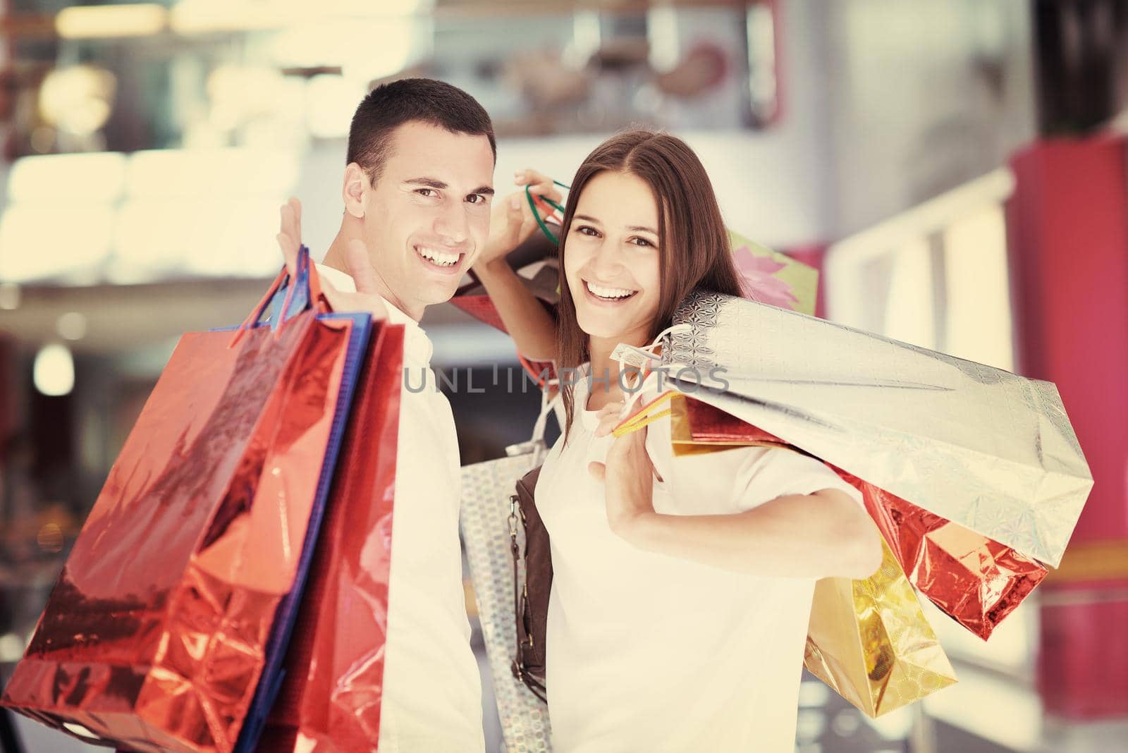 happy young couple with bags in shopping centre mall