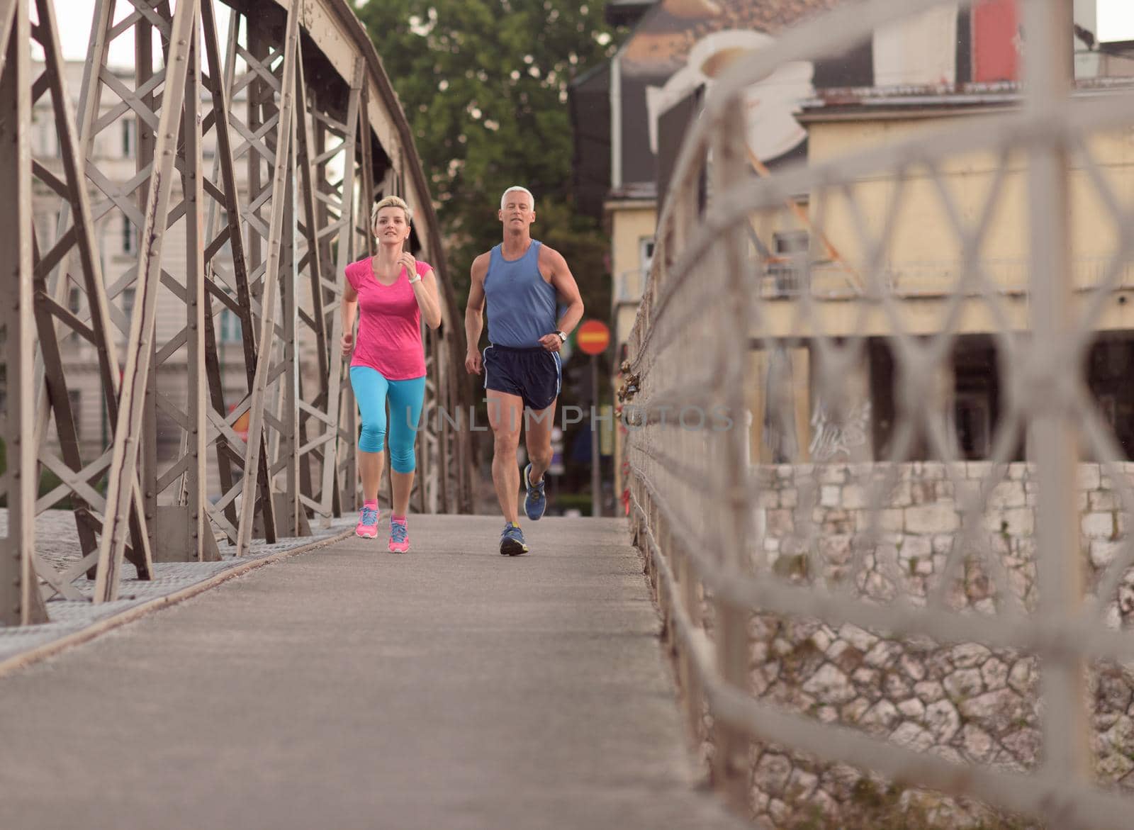 healthy mature couple jogging in the city  at early morning with sunrise in background