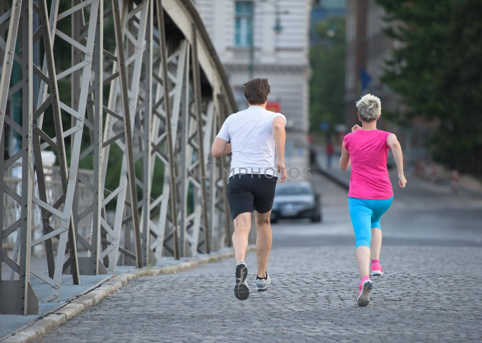 healthy mature couple jogging in the city  at early morning with sunrise in background