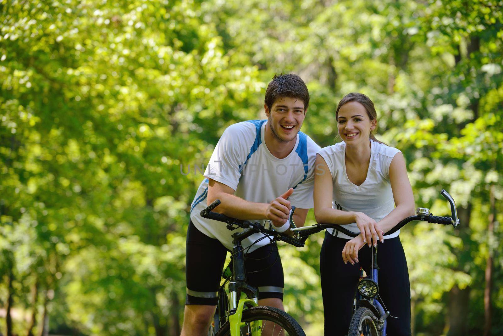 Happy couple ridine bicycle outdoors by dotshock