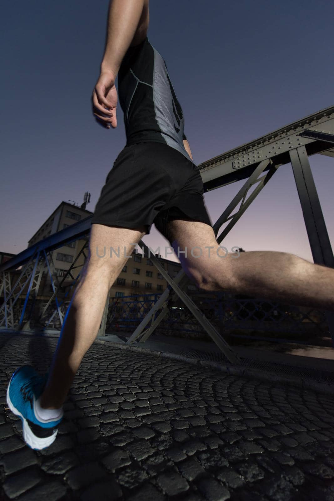 urban sports, young healthy man jogging across the bridge in the city at early morning in night