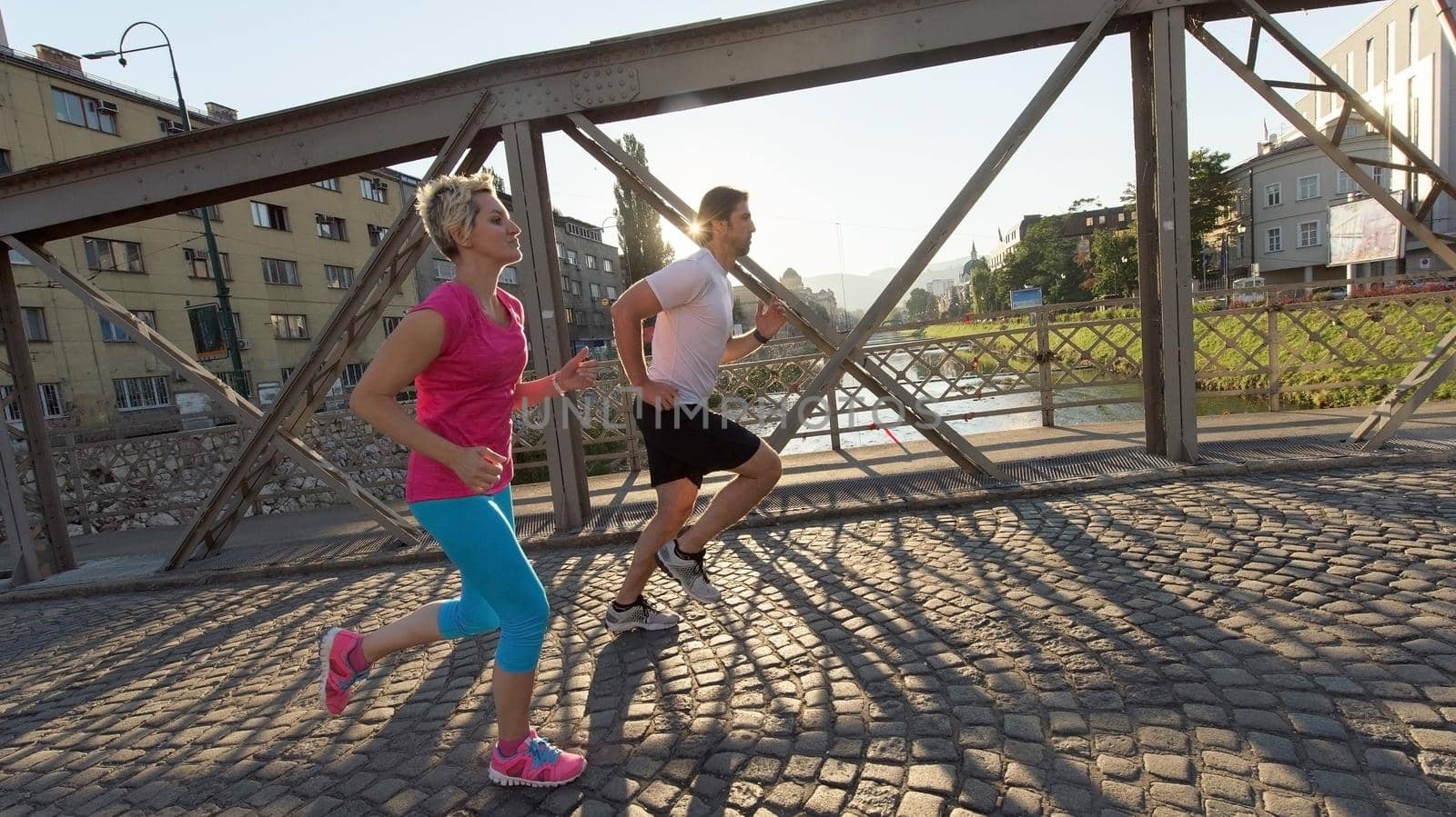 healthy mature couple jogging in the city  at early morning with sunrise in background