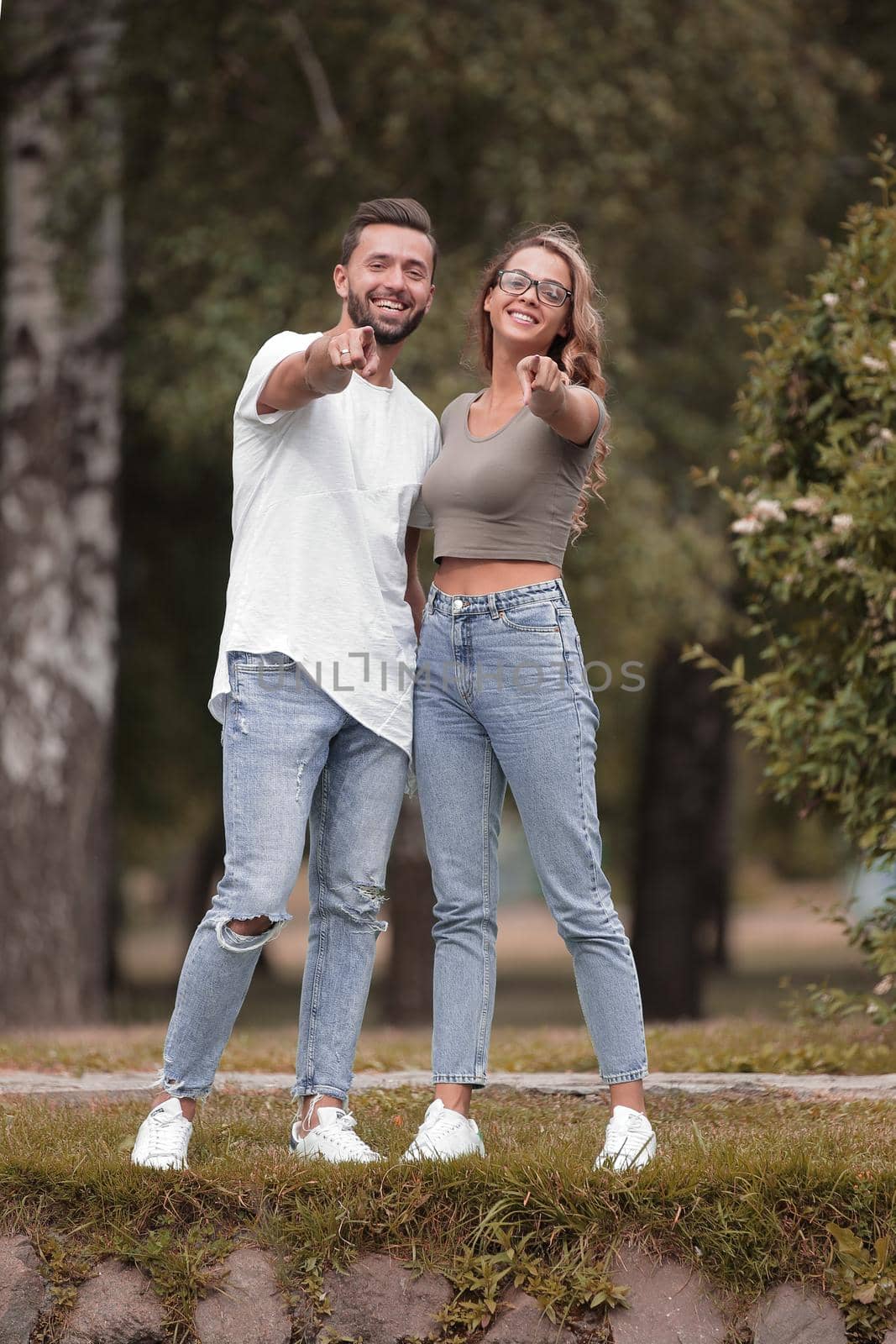 loving couple standing in the Park and pointing at you by asdf