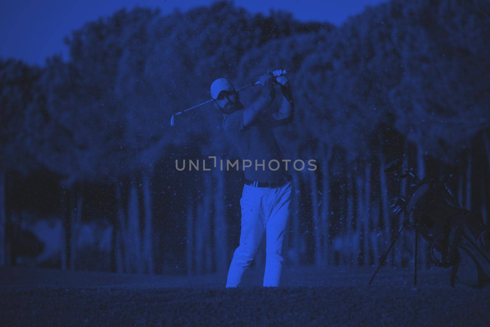 golfer shot ball from sand bunker at golf course with beautiful sunset in background duo tone