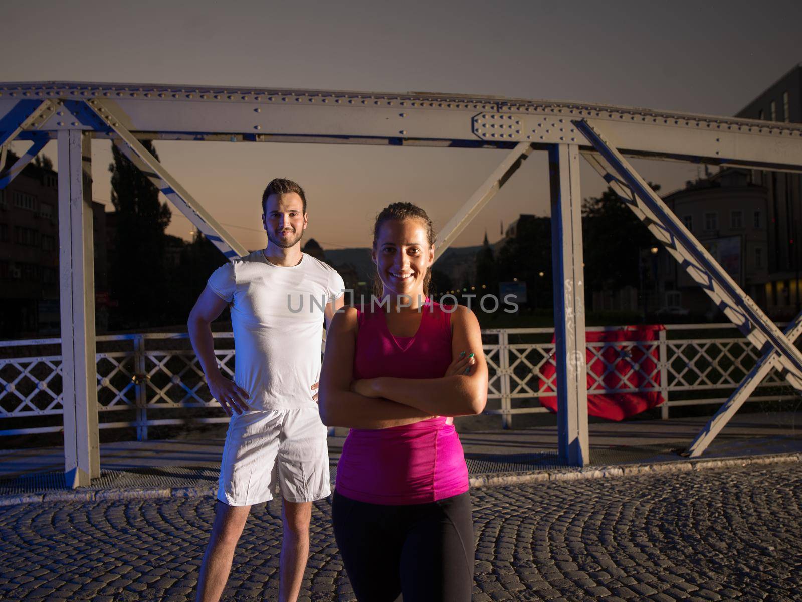 urban sports, portrait of a healthy couple jogging across the bridge in the city at early morning in night