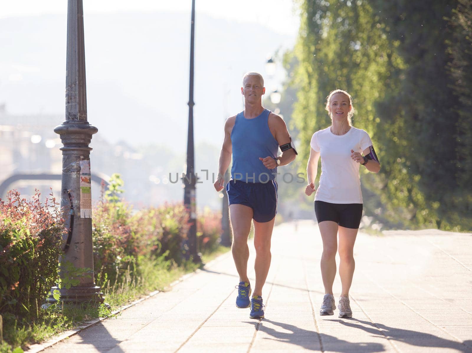 healthy mature couple jogging in the city  at early morning with sunrise in background