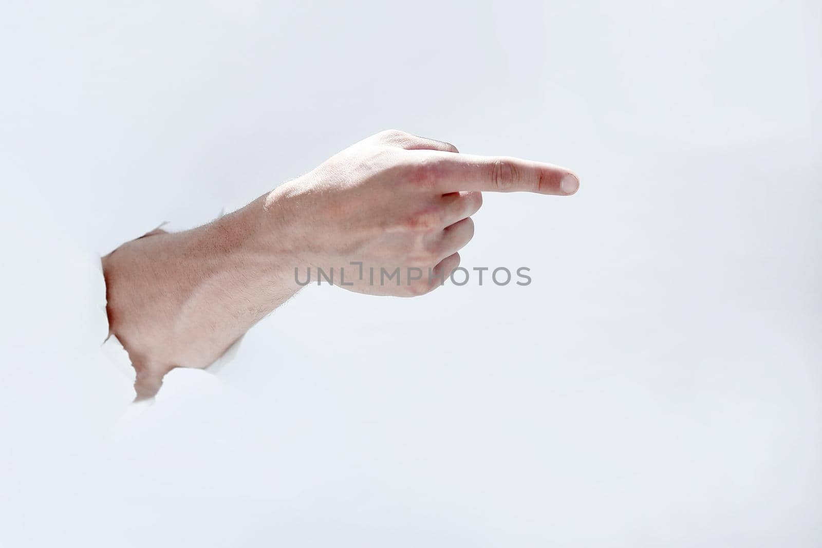 man hand breaking through the paper and pointing to a copy of the space.photo with space for text