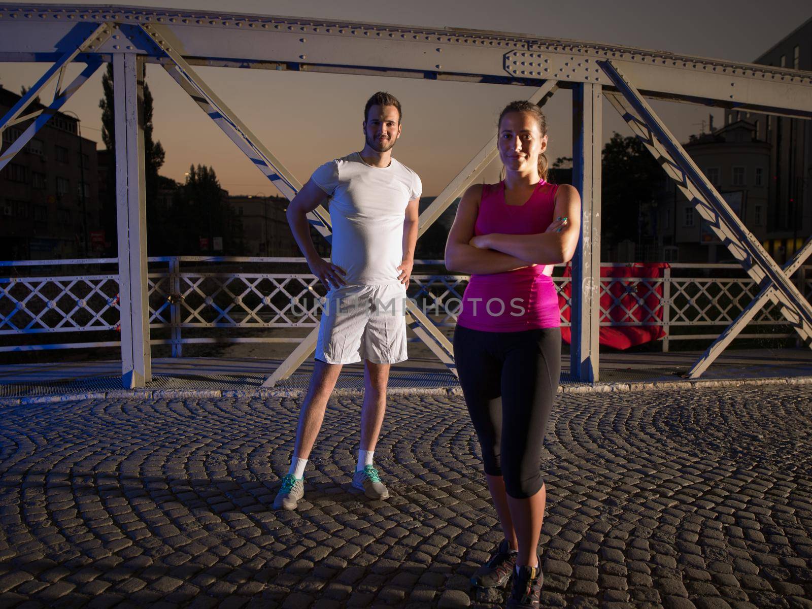 portrait of couple jogging across the bridge in the city by dotshock