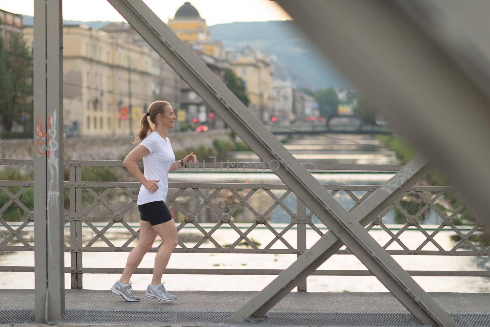 sporty woman running  on sidewalk by dotshock