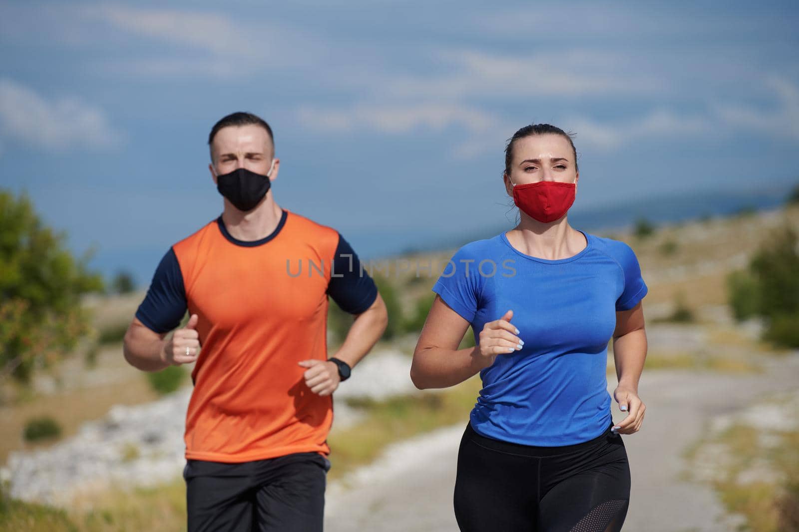 Couple running in nature at morning wearing protective face masks