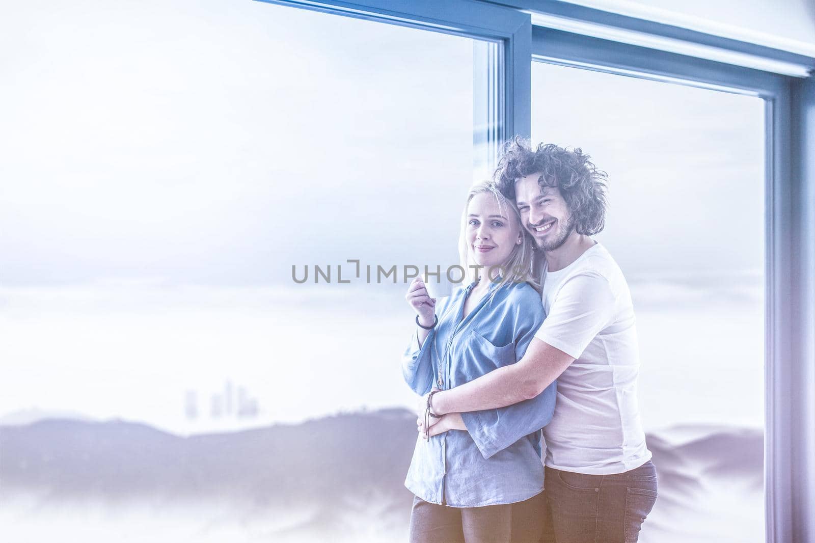 romantic happy young couple enjoying morning coffee by the window on cold winter day at home