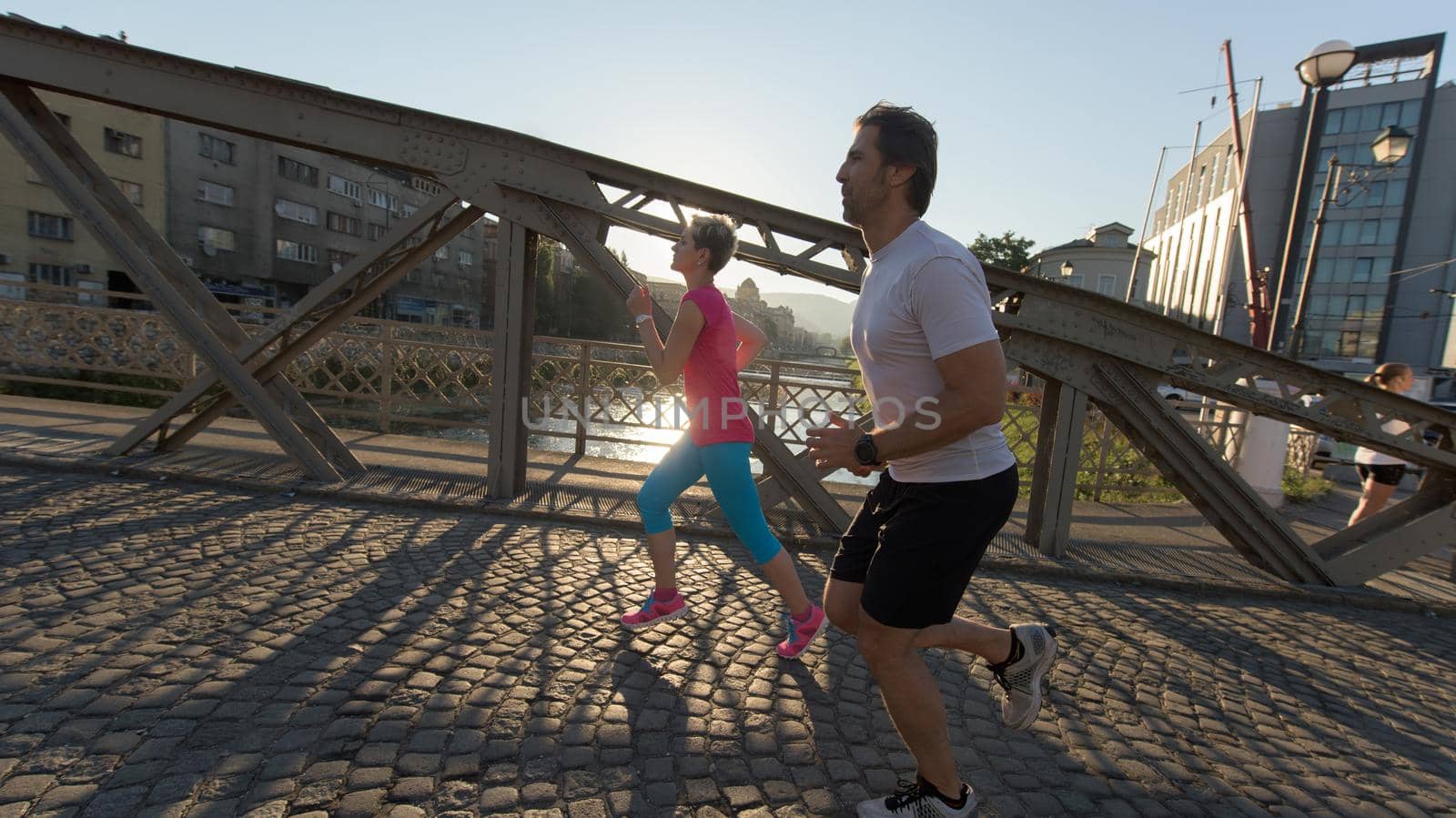 healthy mature couple jogging in the city  at early morning with sunrise in background