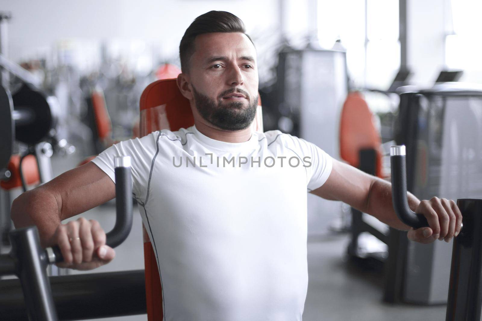 young man does weight training in the gym by asdf