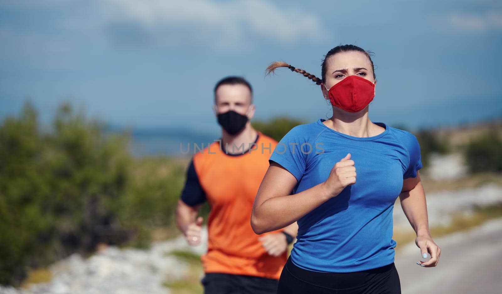 Couple running in nature at morning wearing protective face masks