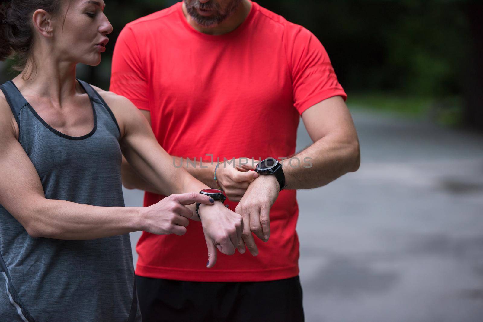 Young sporty couple using smart watches starting their timer before jogging