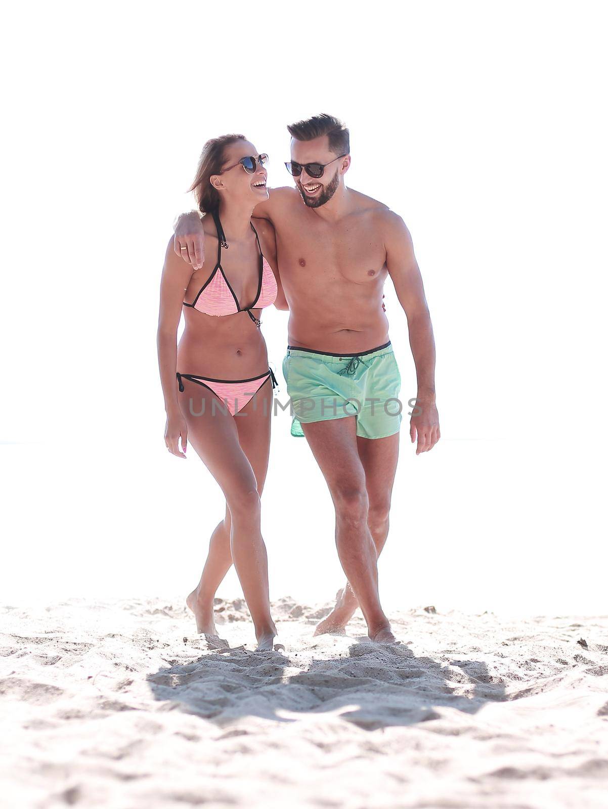 Young couple holding hands and walking on beach. by asdf