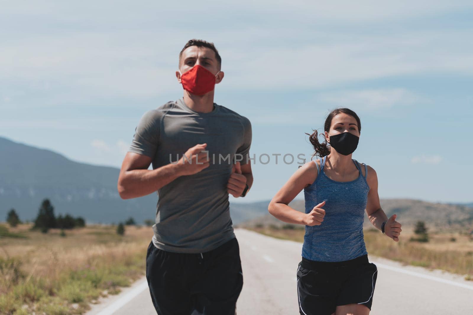 Young man and woman in protective masks running and doing exercises outdoors in the morning. Sport, Active life Jogging during quarantine. Covid-19 new normal. Selective focus. by dotshock