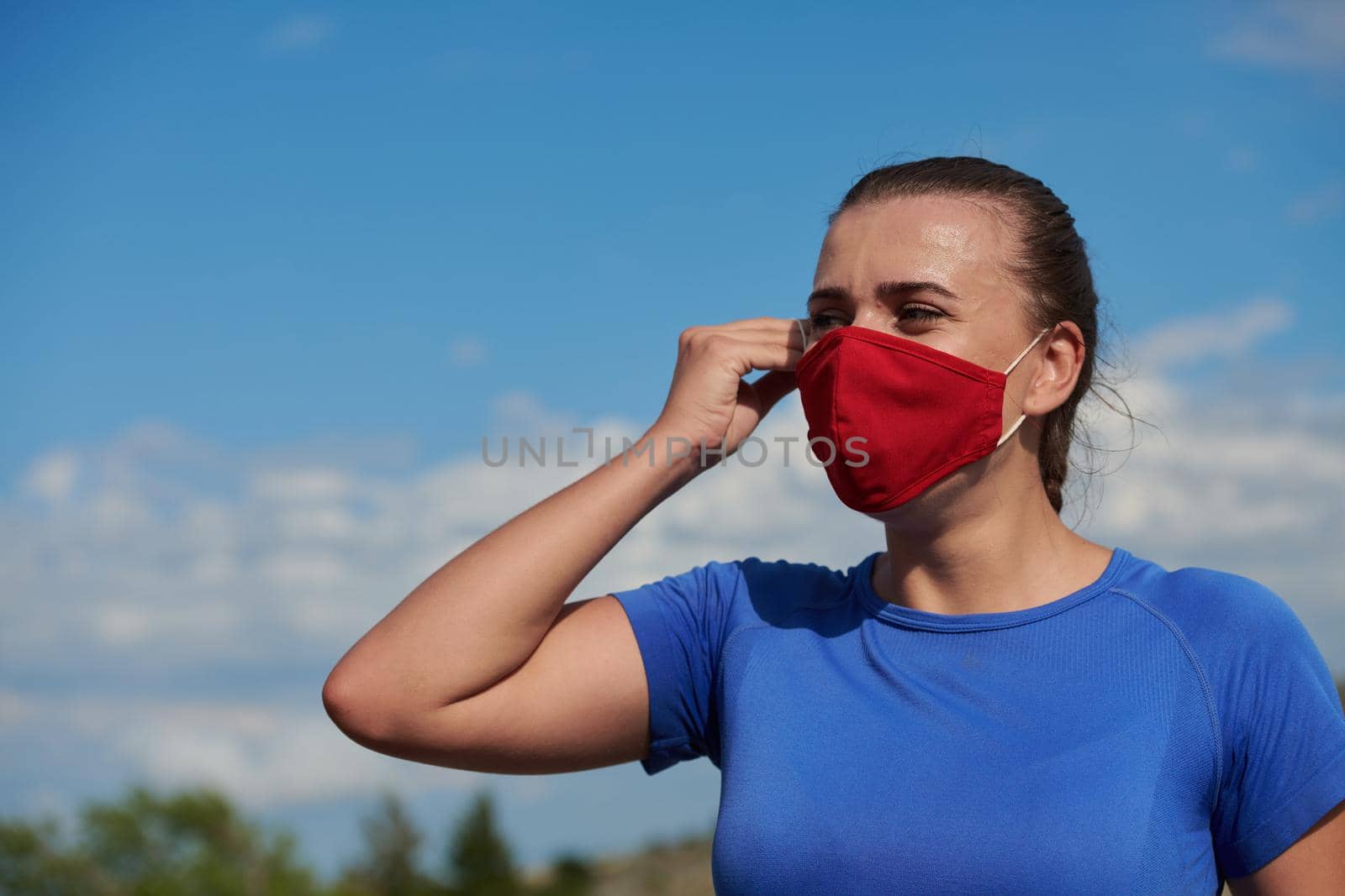 sporty woman with protective face mask having a break and relaxing after running