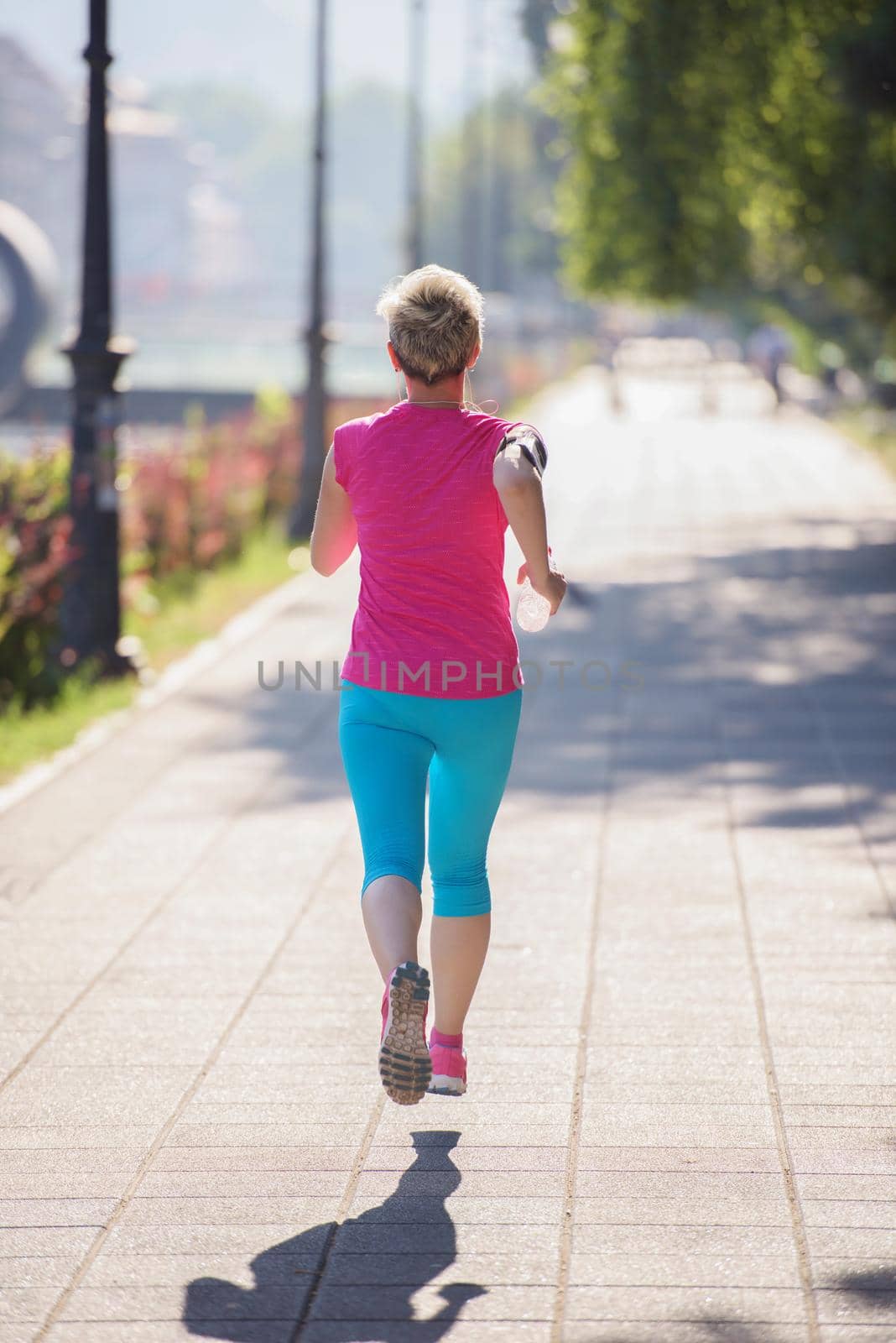 sporty woman running  on sidewalk by dotshock